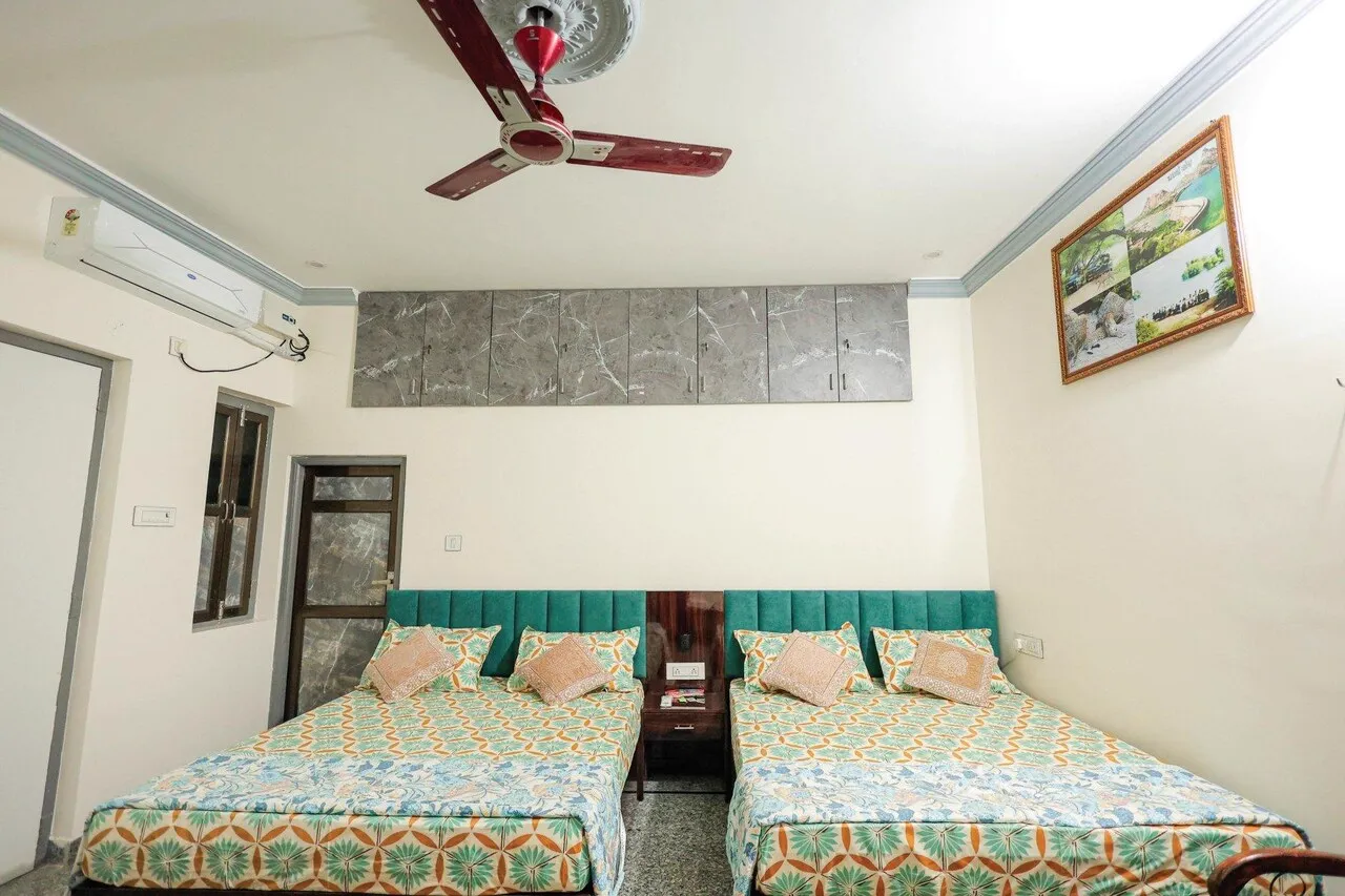 Three queen beds with clean traditional Rajasthani patterned bedspreads in Deluxe AC Room at The Jawai Niwas