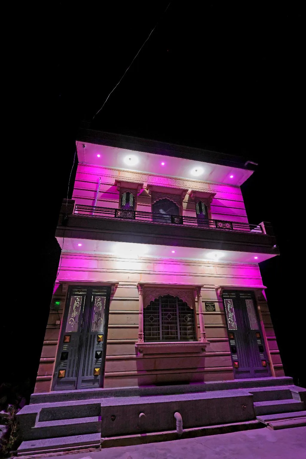 The Jawai Niwas entrance gate and parking area lit up under night sky in Sumerpur